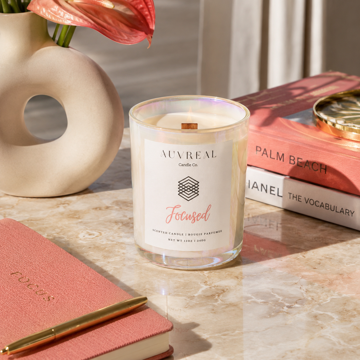 Candle labeled 'Focused' by Auvreal on a marble surface with books and a vase in the background