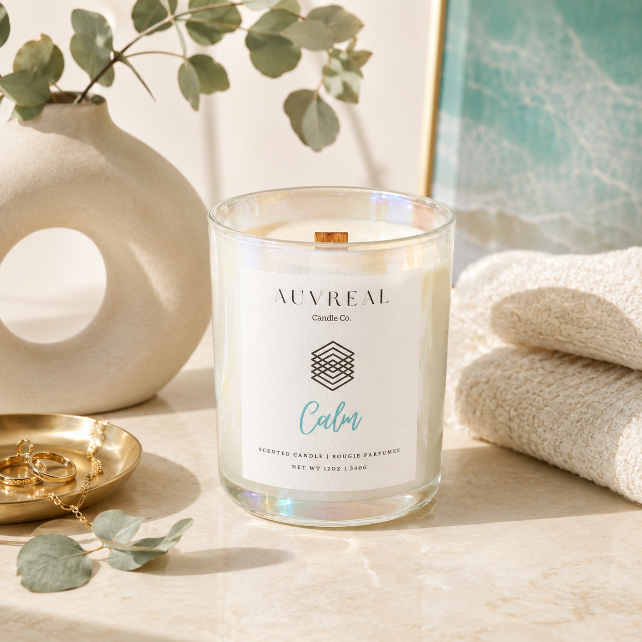 Auvreal Calm candle on a table with eucalyptus leaves and a vase in the background